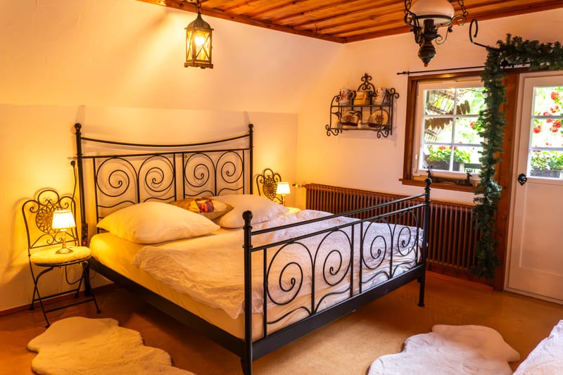 Schlafzimmer mit schmiedeeisernem Bett unter Holzdecke