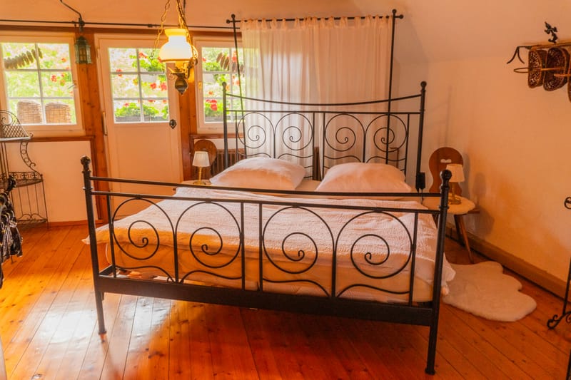 Schlafzimmer mit schmiedeeisernem Bett und Holzboden
